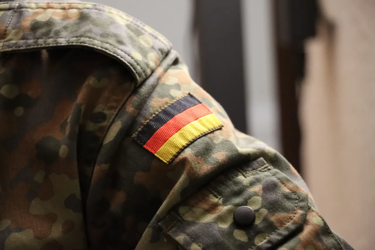Nahaufnahme einer Tarnuniform mit einem Aufnäher der deutschen Flagge auf der Schulter.