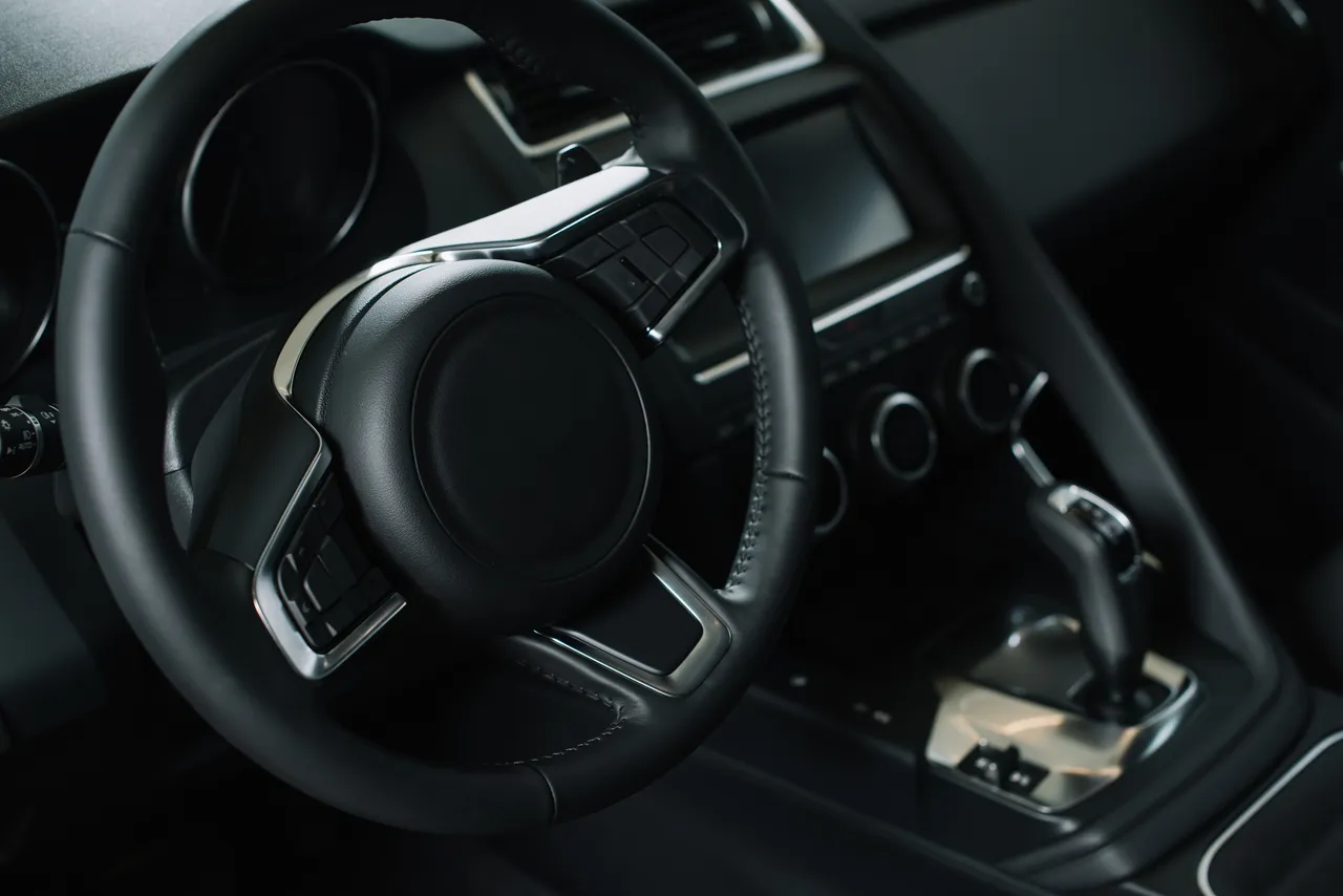 Innenraum eines modernen Autos mit schwarzem Lederlenkrad und zentralem Bildschirm.
