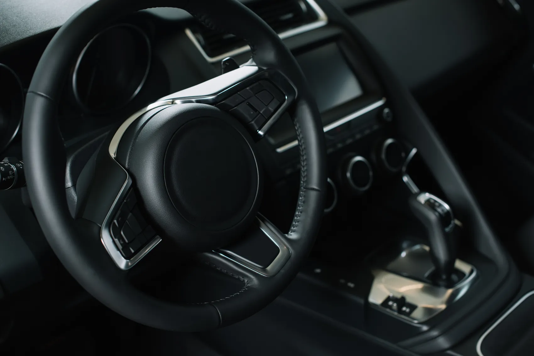 Innenraum eines modernen Autos mit schwarzem Lederlenkrad und zentralem Bildschirm.
