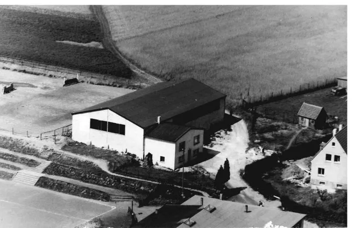Historische Reithalle in Kierspe, aufgenommen aus der Vogelperspektive. Das Gebäude mit Satteldach steht neben Wohnhäusern und Feldern.