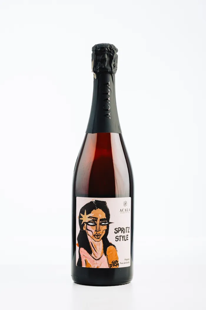 Flasche alkoholfreier Spritz in Rot mit grafischem Etikett einer Frau mit Sonnenstrahlen im Gesicht.