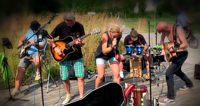 Die Band „Der kleine Dicke Junge“ tritt live auf einer Außenbühne mit Gitarren, Gesang und Perkussion auf.
