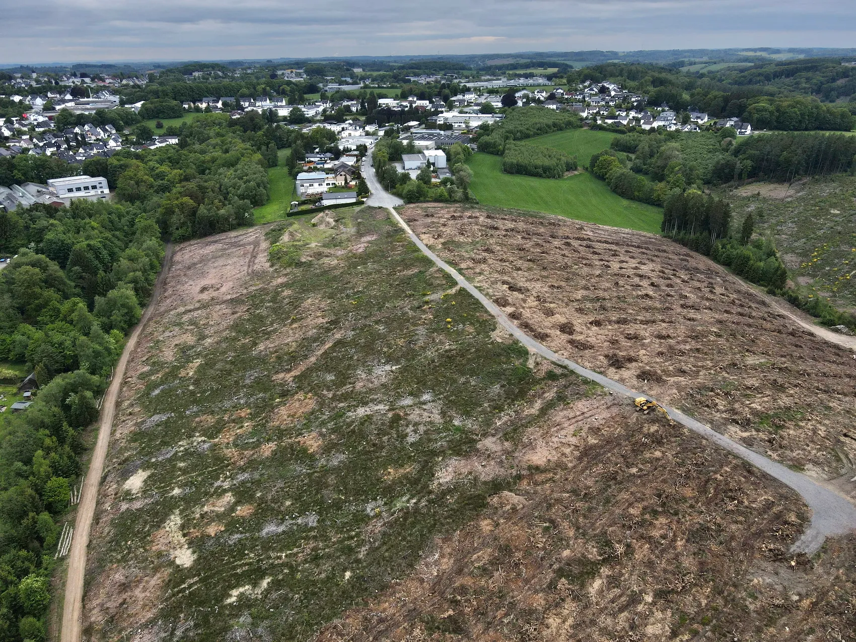 Gerodete Fläche für das geplante Industriegebiet Leifersberge, im Hintergrund eine Wohnsiedlung und bewaldete Hügel.