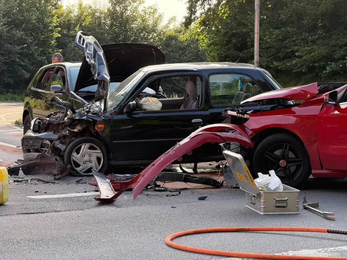 Schwer beschädigte Autos nach einem Unfall auf der L528. Im Vordergrund Trümmerteile und eine Ausrüstungskiste, im Hintergrund Einsatzkräfte.
