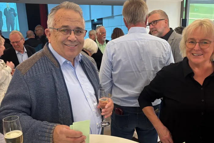 Ein lächelnder Mann mit Brille und blauem Cardigan hält ein Glas Sekt beim 6. Herscheider Ehrenamtstag.