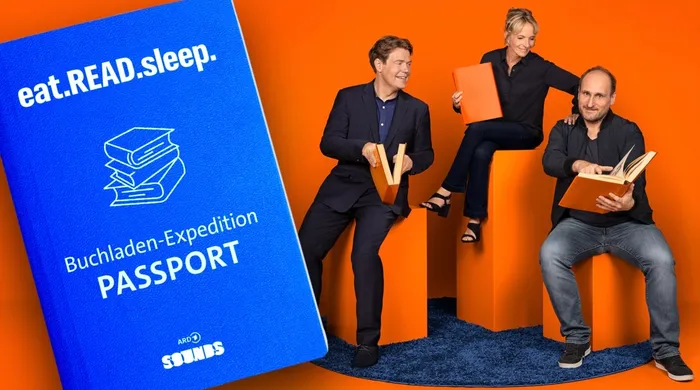 Drei Personen sitzen und stehen vor einem riesigen blauen Buch-Pass, der mit dem Slogan „eat.READ.sleep.“ und dem Logo von NDR Kultur bedruckt ist. Eine Frau hält ein Buch hoch, während die beiden Männer Bücher lesen.