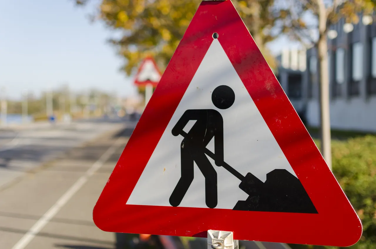 Rotes Warndreieck mit schwarzer Silhouette einer Person, die mit Schaufel arbeitet. Das Schild weist auf Straßenbauarbeiten hin.