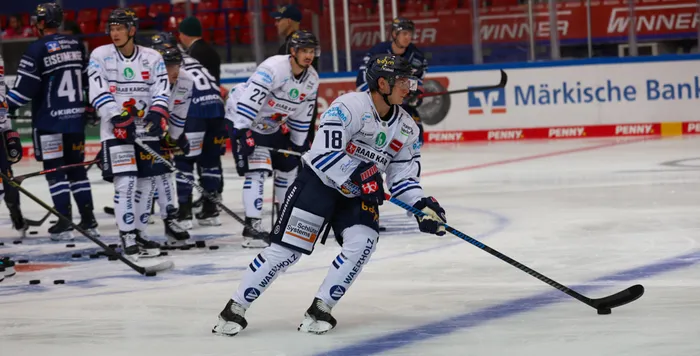 Ein Eishockeyspieler der Iserlohn Roosters mit der Nummer 18 führt den Puck auf dem Eis.