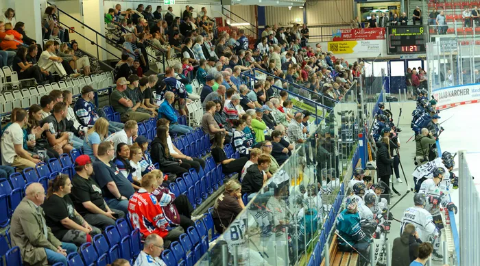Zahlreiche Fans auf blauen Tribünen beobachten das Eishockey-Training der Iserlohn Roosters.