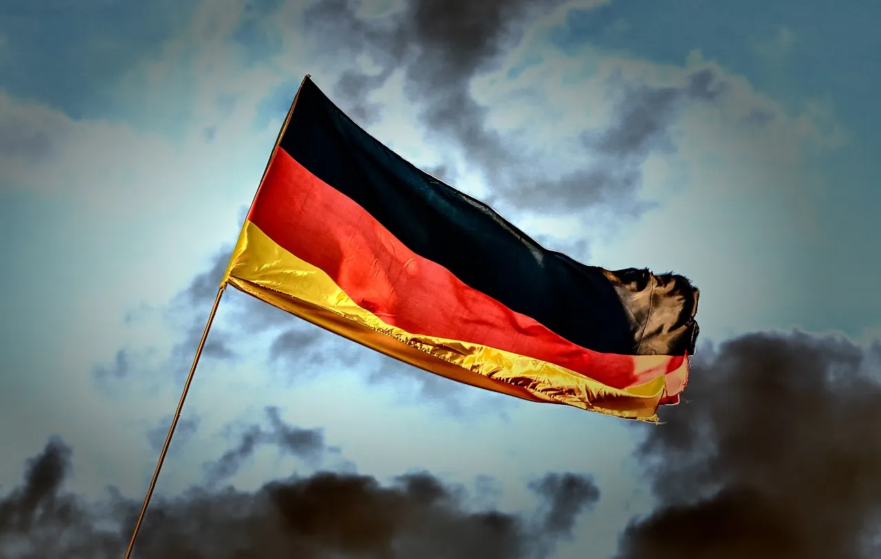 Die deutsche Flagge weht vor einem bewölkten Himmel.