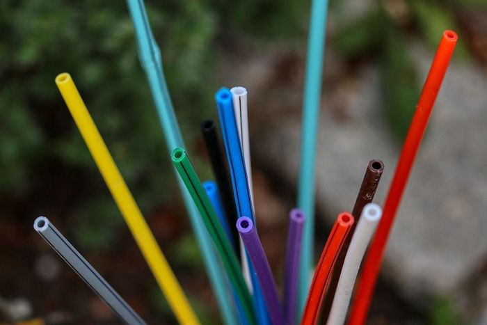 Bunte Glasfaserkabel stecken in einem Haufen, vor einem unscharfen grünen Hintergrund. Das Bild symbolisiert den Stillstand des Glasfaserausbaus.