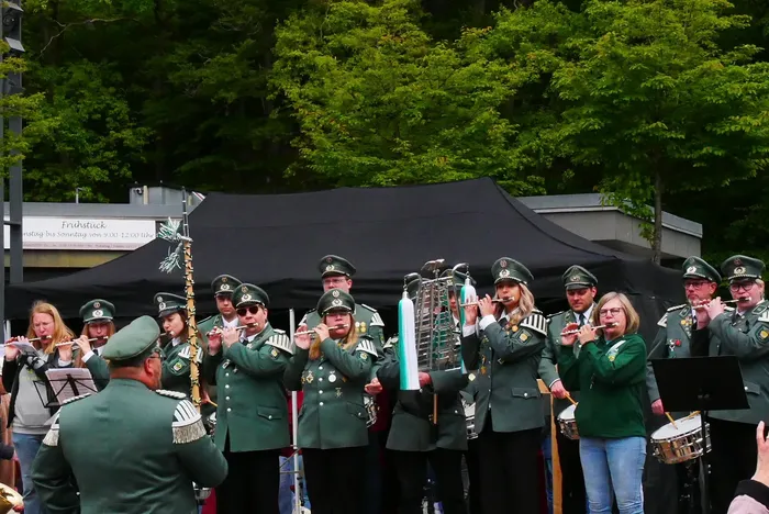 Musikverein in grünen Uniformen spielt auf dem Rathausplatz vor einem Zelt. Mehrere Musiker spielen Klarinetten, während andere Trompeten und Posaunen spielen.