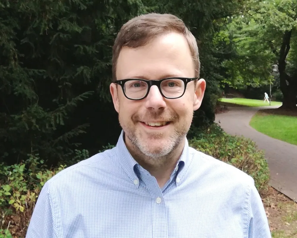 Porträt von Ulrich Thoden, verteidigungspolitischer Sprecher der Linken, mit Brille und kurzem Bart im Freien.