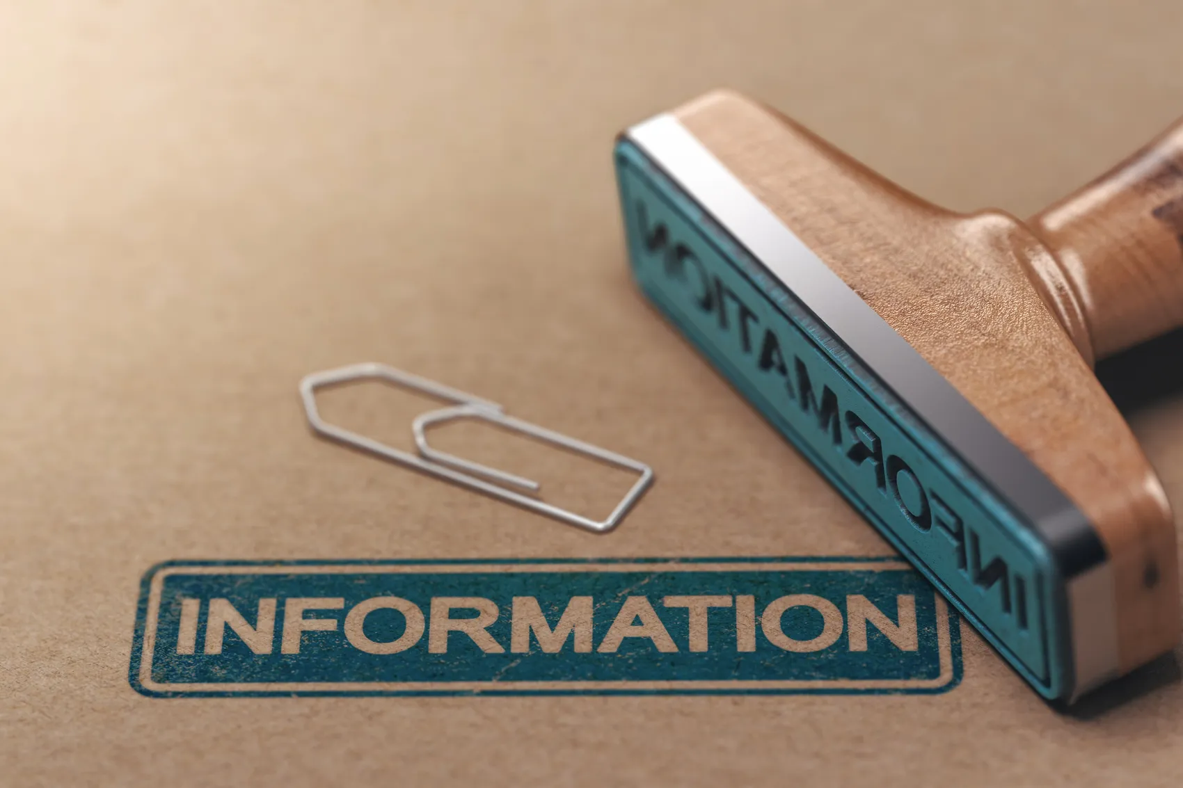 Ein Stempel mit dem Wort „INFORMATION“ und eine Büroklammer liegen auf einem hellbraunen Untergrund.
