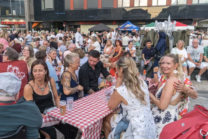 Menschen sitzen an rot-weiß karierten Tischen bei der italienischen Nacht in Lüdenscheid.