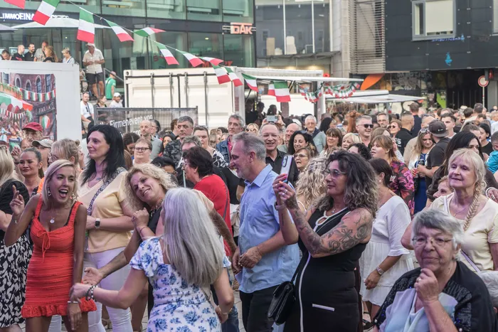 Eine Menschenmenge feiert die italienische Nacht in Lüdenscheid unter italienischen Wimpelketten.