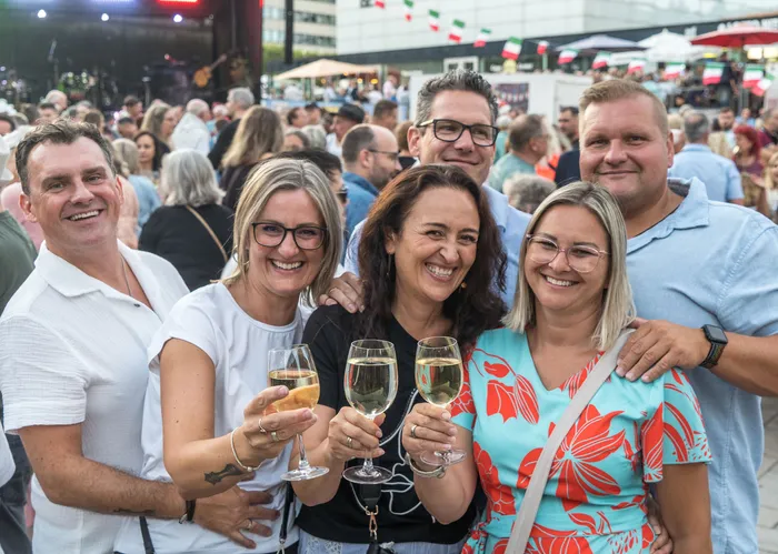 Eine Gruppe lachender Menschen hält bei der italienischen Nacht in Lüdenscheid Gläser mit Weißwein hoch.