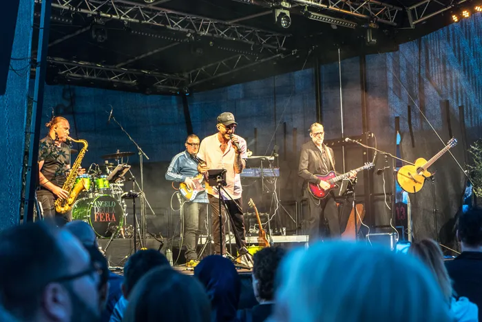 Eine Band mit Saxophonist, Gitarristen und Sänger tritt live auf einer Bühne bei der italienischen Nacht in Lüdenscheid auf.