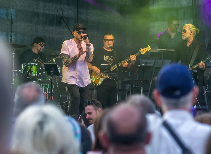 Eine Band tritt bei der italienischen Nacht in Lüdenscheid auf einer Bühne auf, während im Vordergrund Zuschauer zu sehen sind.