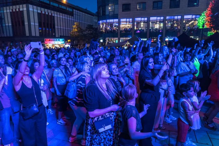 Eine Menschenmenge bei der italienischen Nacht in Lüdenscheid unter blauem Licht, wobei viele Personen ihre Smartphones hochhalten.