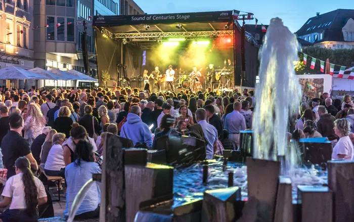 Eine große Menschenmenge beobachtet eine Live-Band auf einer beleuchteten Bühne bei der italienischen Nacht in Lüdenscheid.