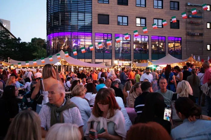 Viele Menschen besuchen die Italienische Nacht auf dem Sternplatz in Lüdenscheid zwischen weißen Zelten und italienischen Flaggen.