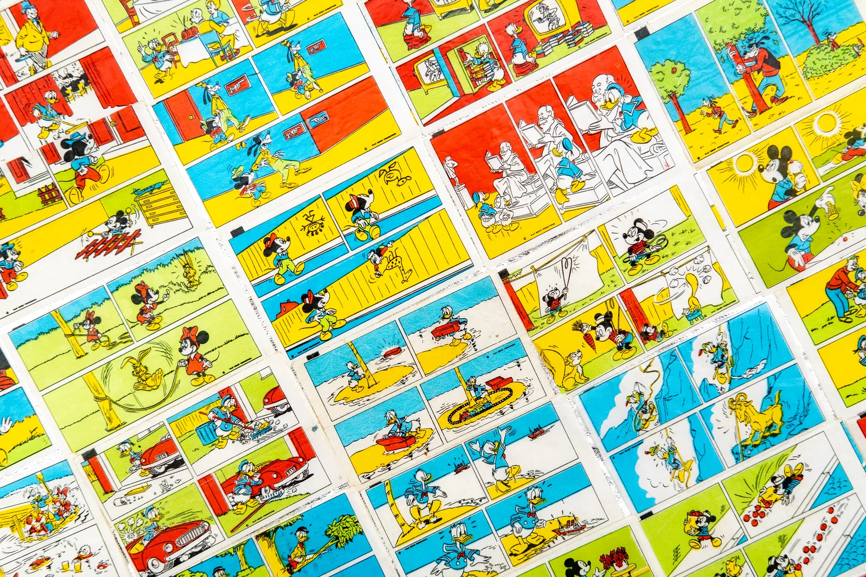 Mehrere Comicstrips mit Donald Duck und Micky Maus, angeordnet auf einer Oberfläche.