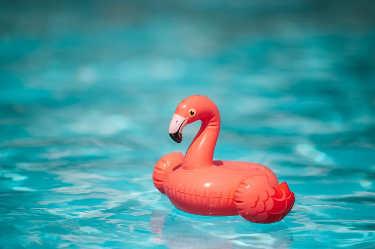 Ein aufblasbarer rosa Flamingo schwimmt auf einem blauen Pool.