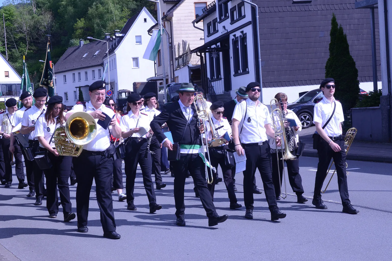 Musikzug marschiert beim Schützenfest in Plettenberg mit Blechblasinstrumenten und in weißen Uniformen durch die Straße.