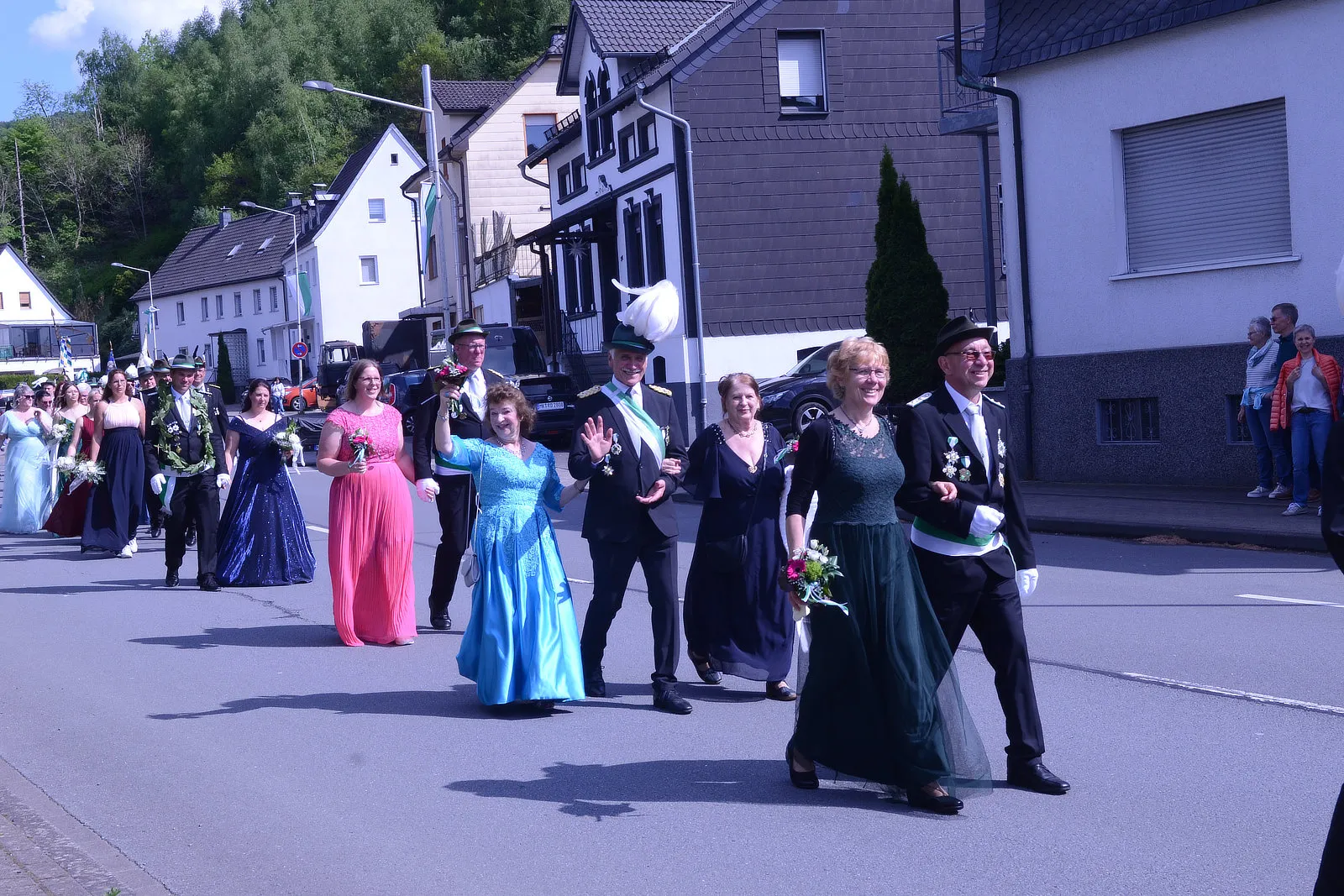 Festumzug mit festlich gekleideten Personen, darunter Paare in Abendgarderobe und Mitglieder einer Schützenkompanie, auf einer Straße in Plettenberg.