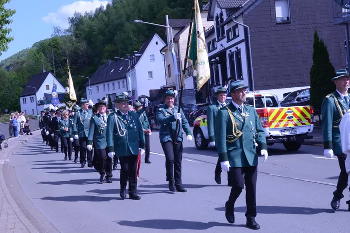 Festumzug mit zahlreichen Mitgliedern des Schützenvereins Grünetal in Plettenberg, die in grünen Uniformen marschieren und Fahnen tragen.