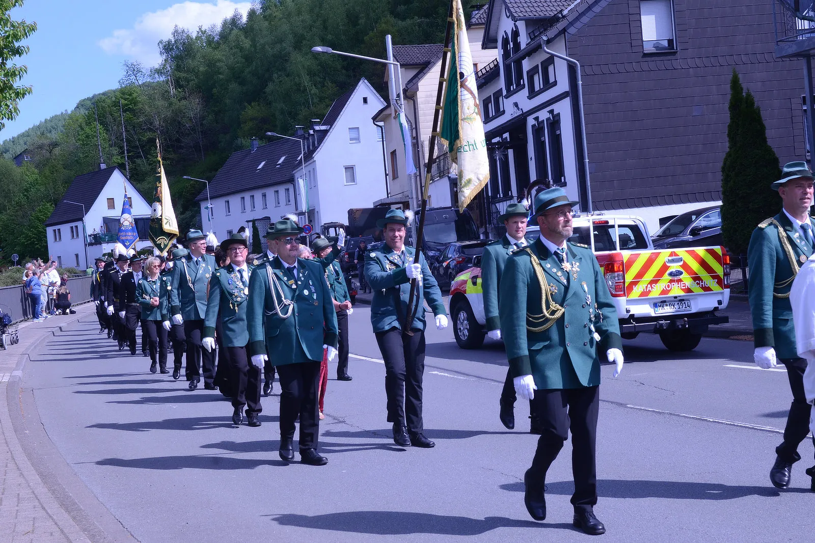 Festumzug mit zahlreichen Mitgliedern des Schützenvereins Grünetal in Plettenberg, die in grünen Uniformen marschieren und Fahnen tragen.