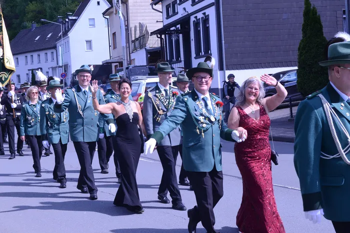 Festumzug mit Mitgliedern des Schützenvereins Grünetal in Plettenberg, die in grünen Uniformen und festlicher Kleidung marschieren und winken.
