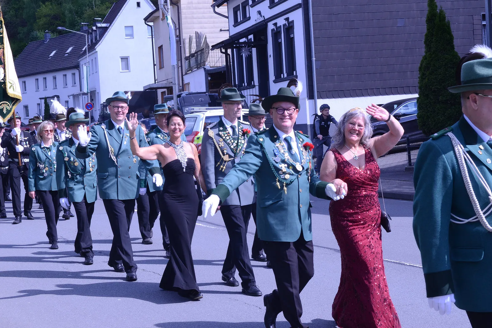 Festumzug mit Mitgliedern des Schützenvereins Grünetal in Plettenberg, die in grünen Uniformen und festlicher Kleidung marschieren und winken.