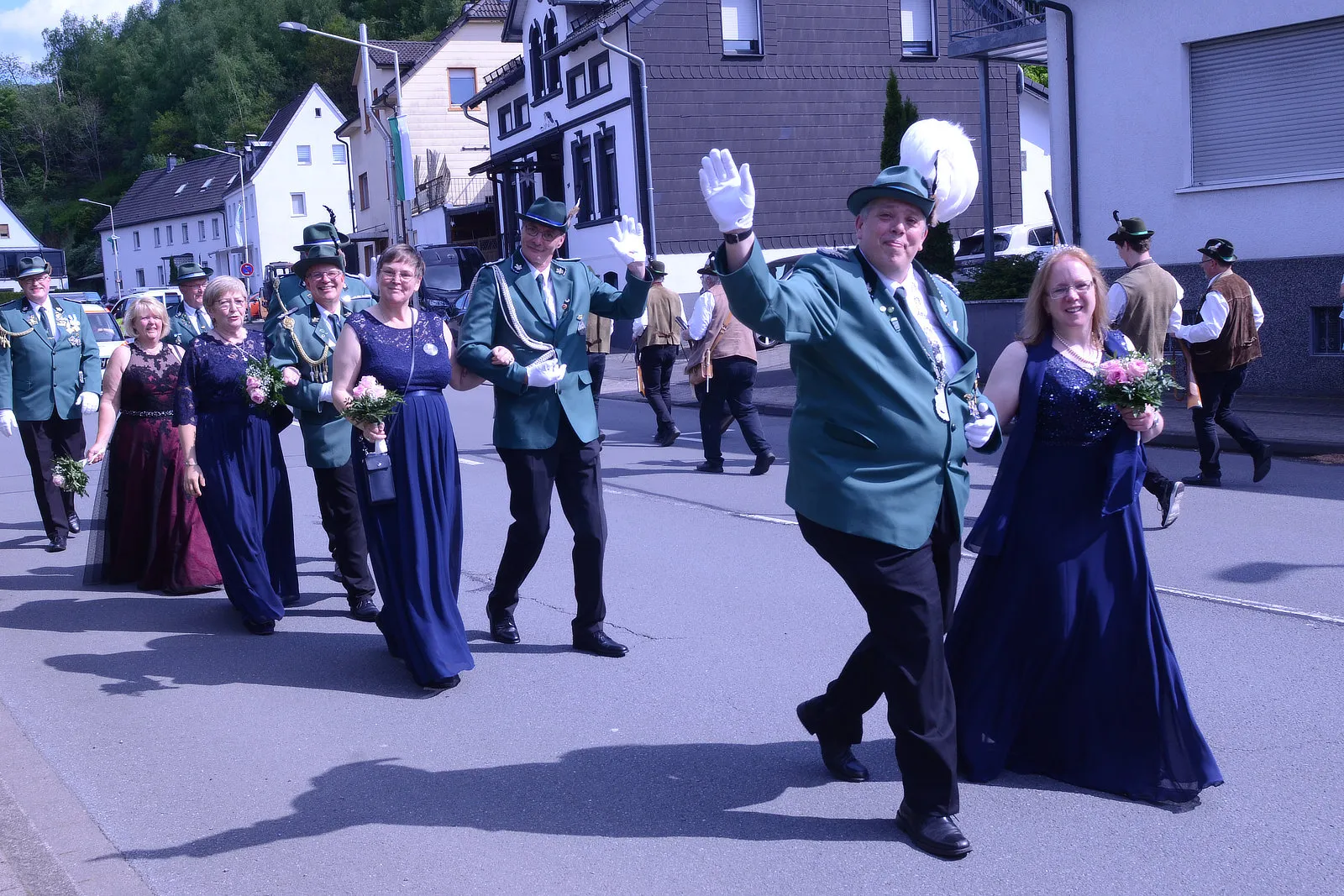 Festzug mit Schützen in grünen Uniformen und festlich gekleideten Begleitern zieht durch eine Stadtstraße.