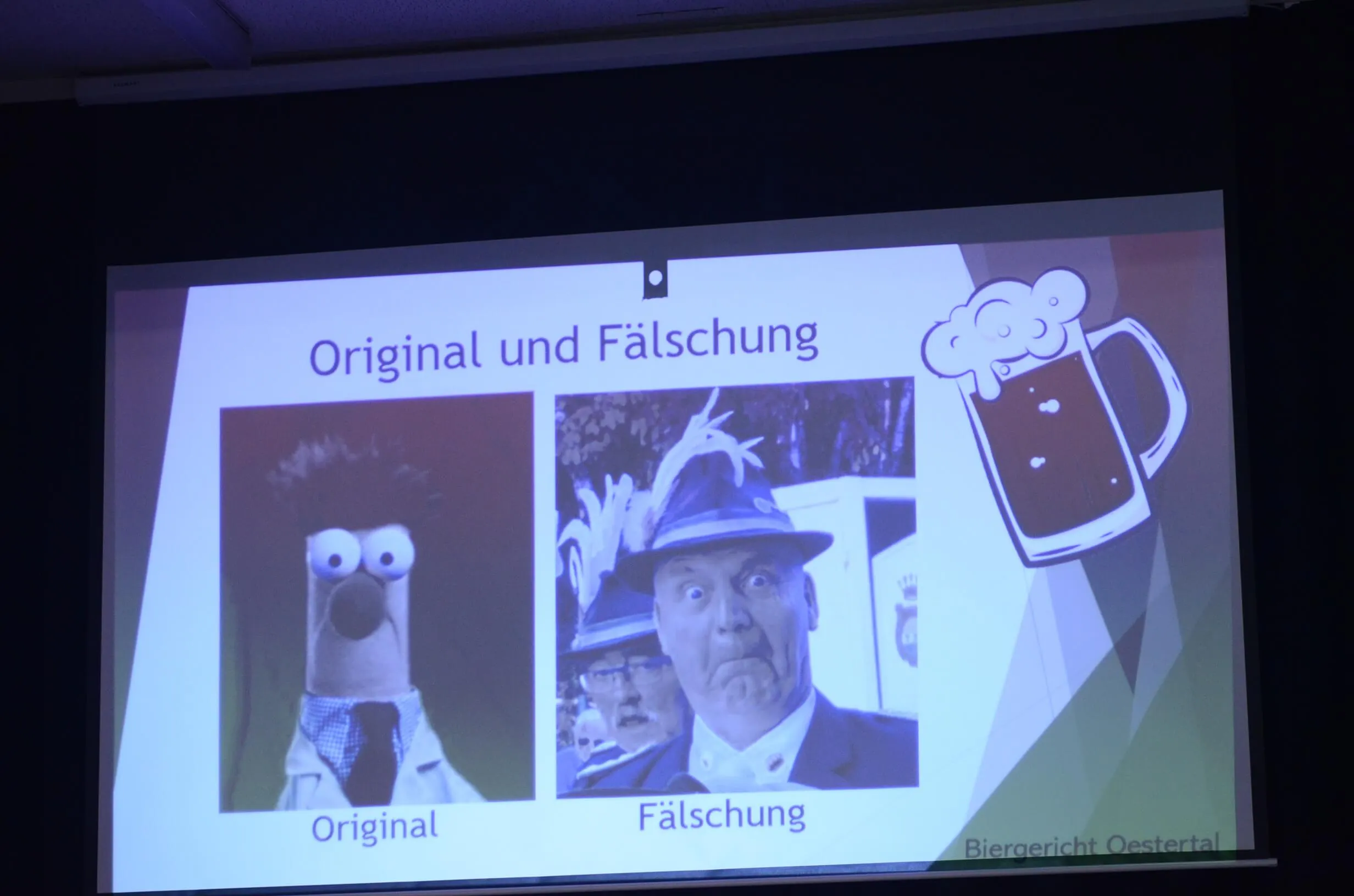 Präsentation mit den Begriffen „Original“ und „Fälschung“ illustriert durch ein Handpuppenbild und ein Porträt eines Mannes in Uniform, daneben eine stilisierte Biergrafik.
