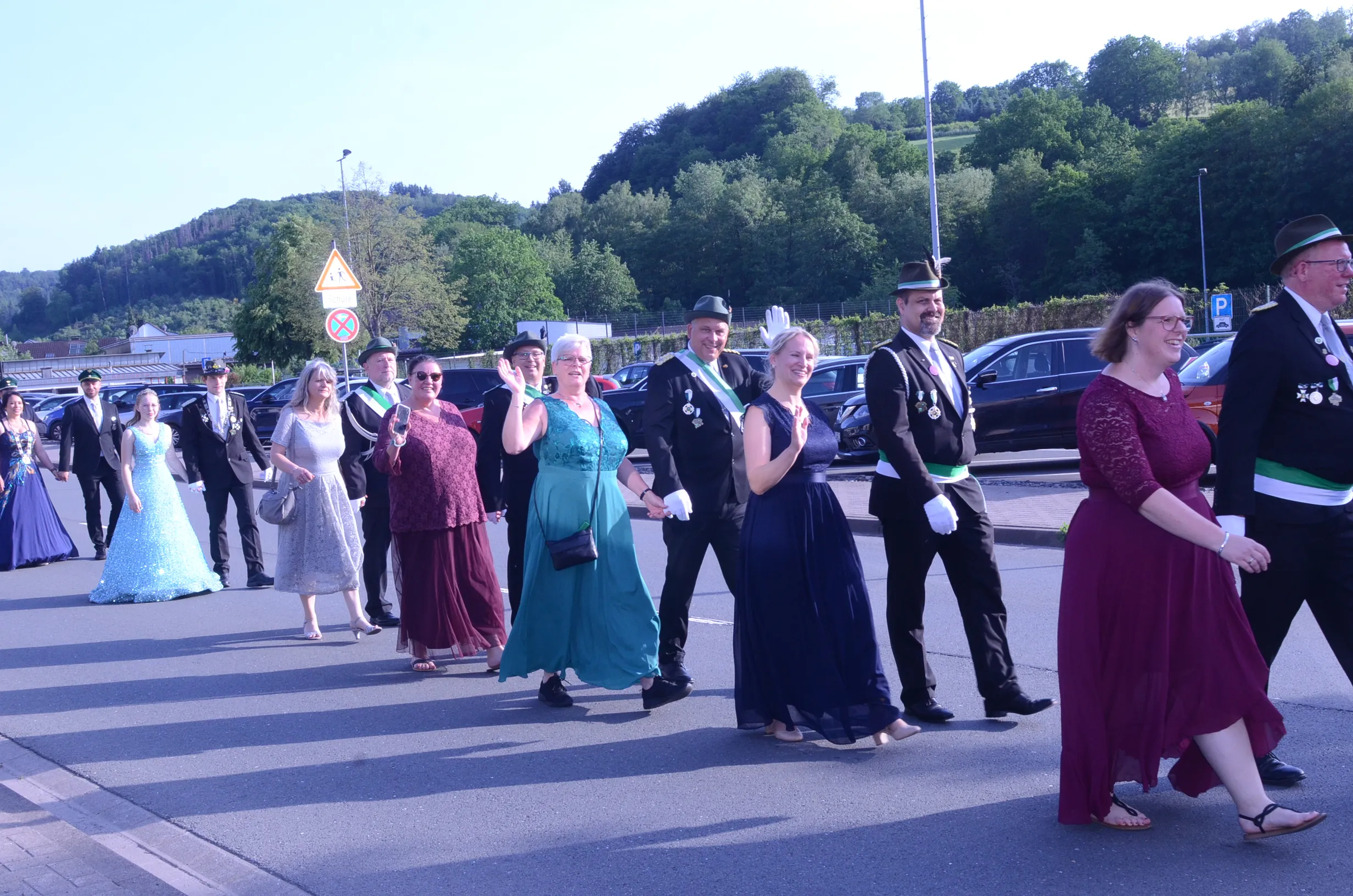 Festzug mit Schützen in historischen Uniformen und festlich gekleideten Begleitern überquert eine Straße im Oestertal.