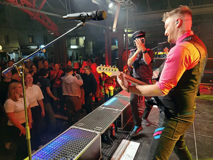 Ein Musiker der Band Hitfluencer spielt auf einer Bühne mit E-Gitarre vor einem Publikum beim Plettenberger Stadtfest.