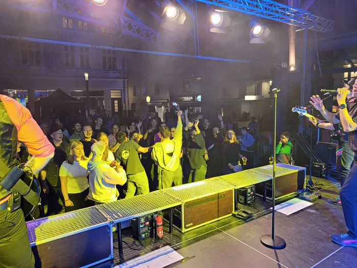 Eine jubelnde Menschenmenge tanzt vor einer beleuchteten Bühne bei einem Live-Konzert.