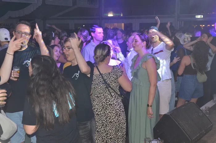 Menschen tanzen und feiern in einem Festzelt bei einer Musikveranstaltung.