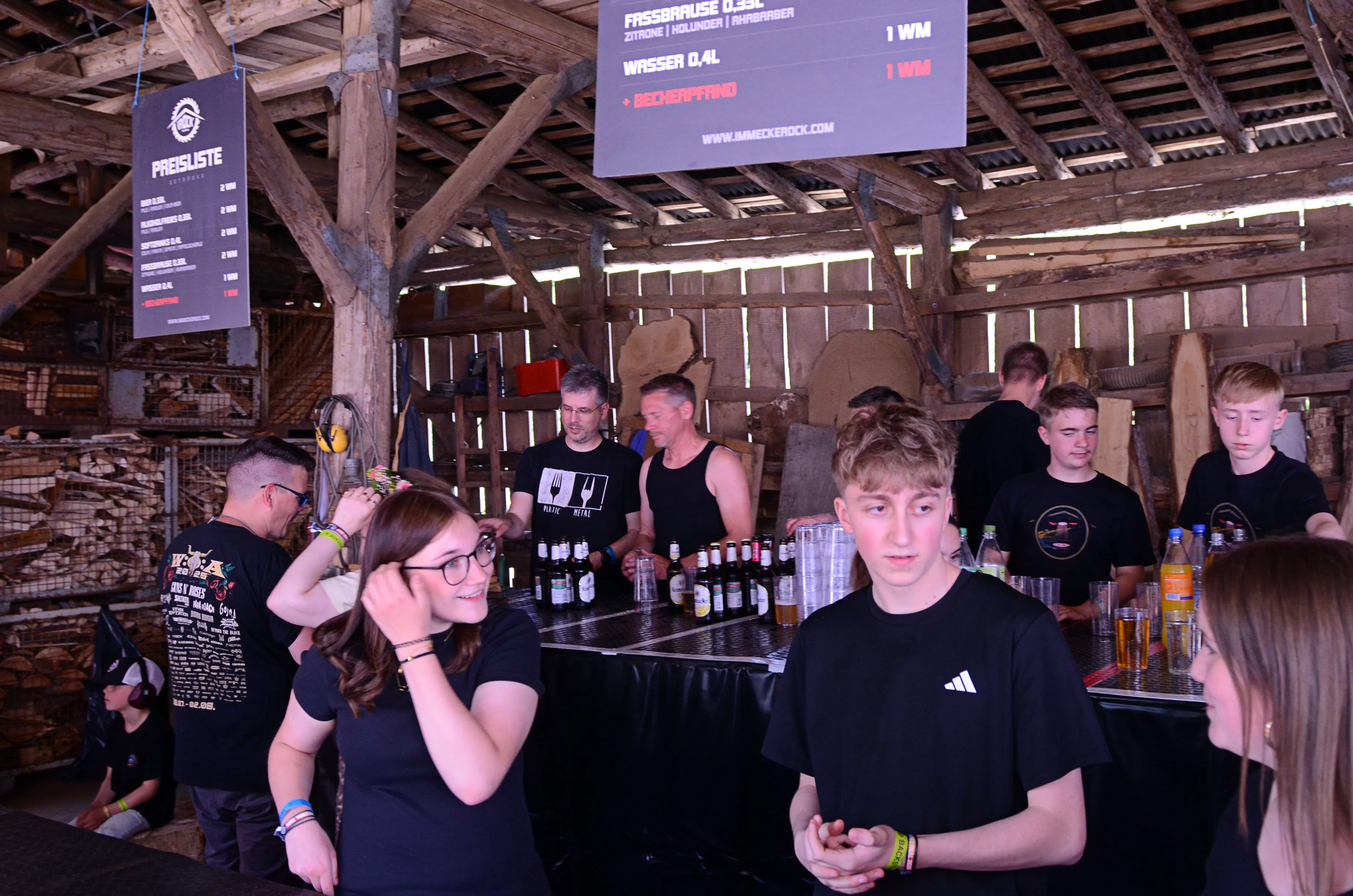 Personen an einer Bar im Freien auf dem Immecke Rock Festival in Plettenberg bestellen und servieren Getränke.