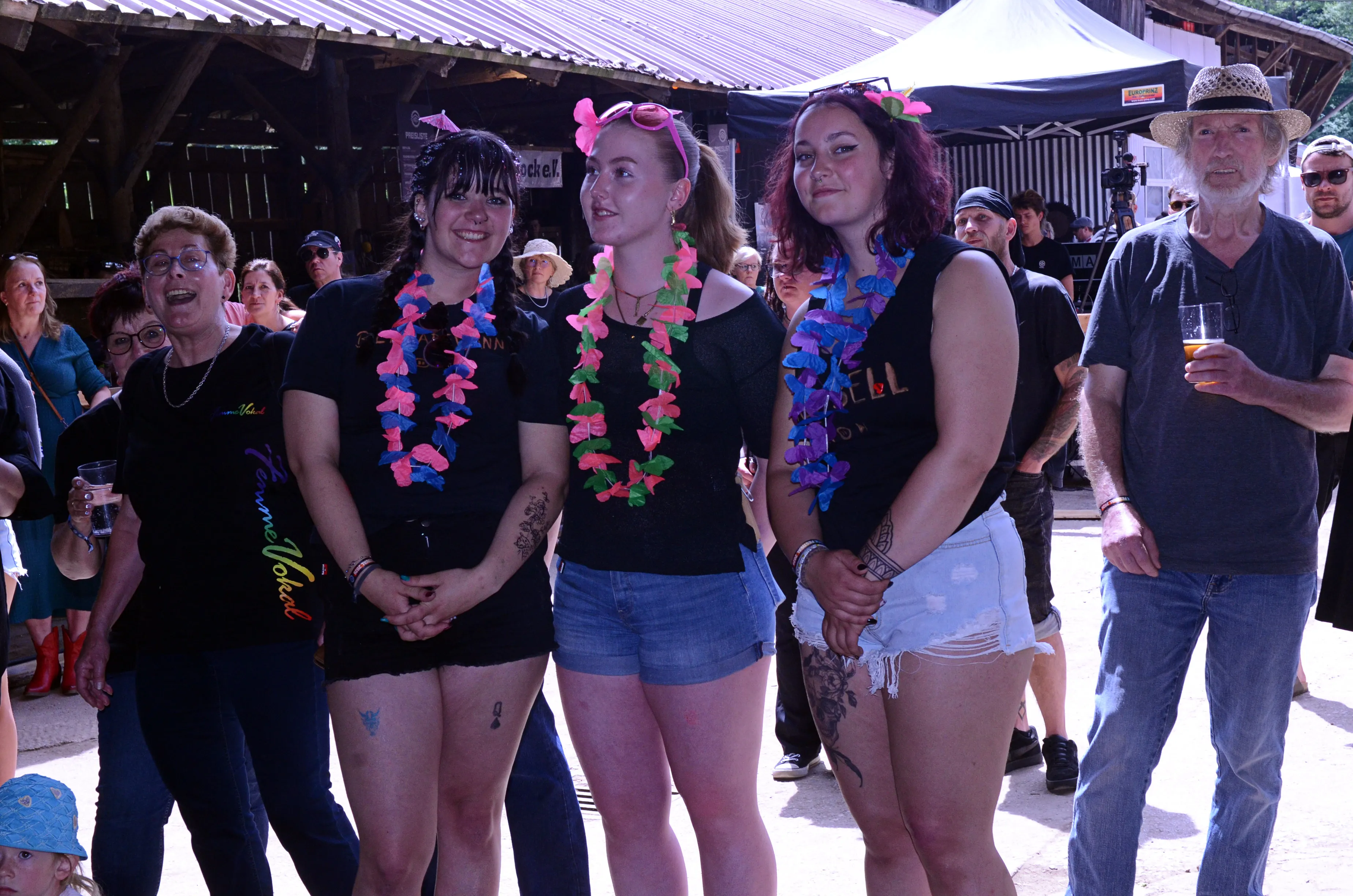 Vier junge Frauen mit Blumenketten und ein Mann mit Cowboyhut stehen auf dem Immecke Rock Festival in Plettenberg.