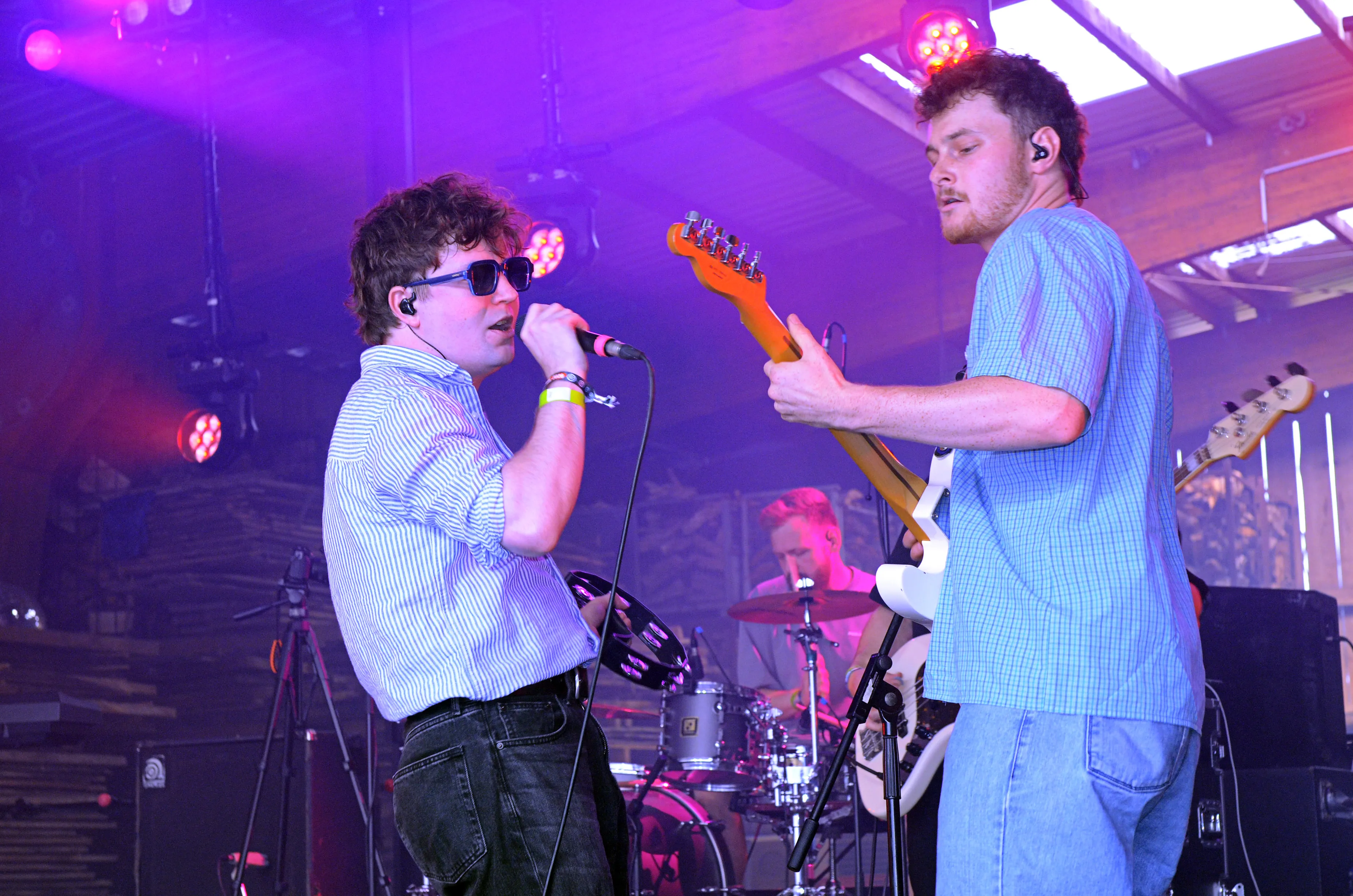 Zwei Musiker auf der Bühne des Immecke Rock Festivals: ein Sänger mit dunkler lockiger Frisur, Sonnenbrille und Streifenhemd sowie ein Gitarrist mit Bart und hellblauem Hemd.