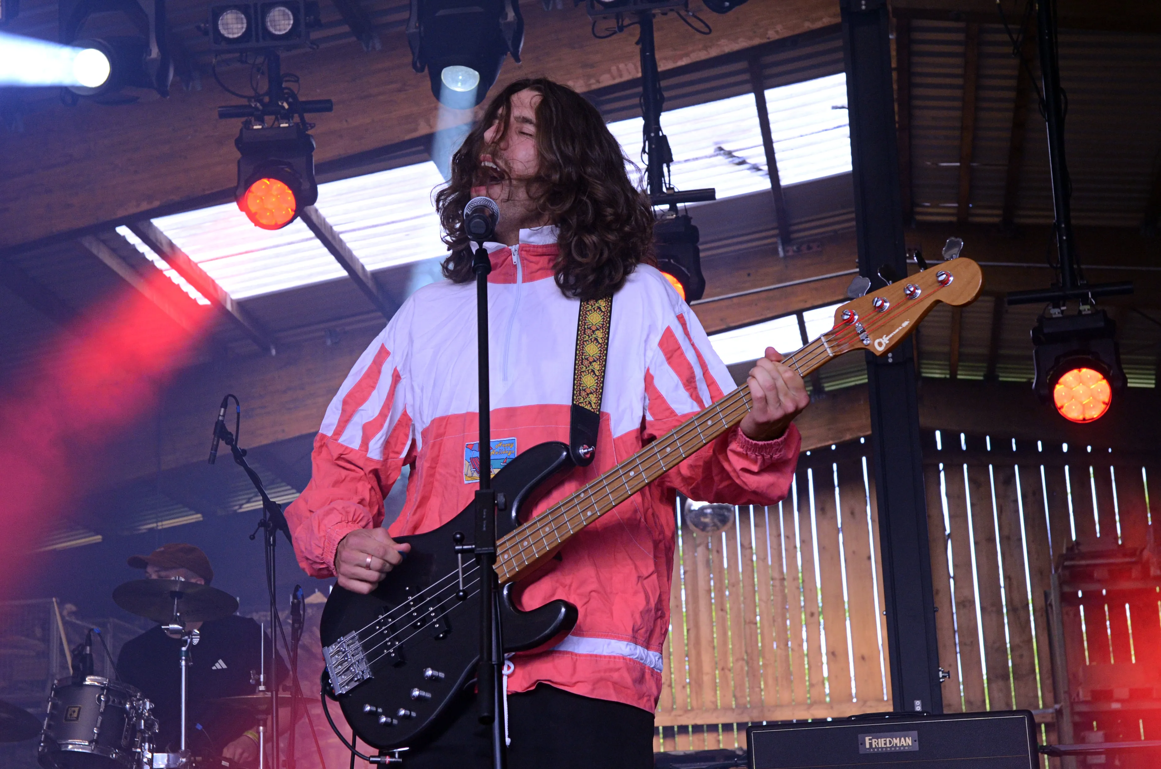 Musiker mit langen Haaren spielt Bass auf einer Open-Air-Bühne vor Publikum bei dem Immecke Rock Festival.