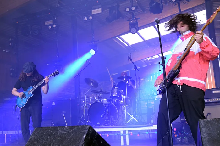 Zwei Musiker auf der Bühne des Immecke Rock Festivals: Ein Gitarrist mit Mütze und ein Sänger mit lockigem Haar und Jacke.