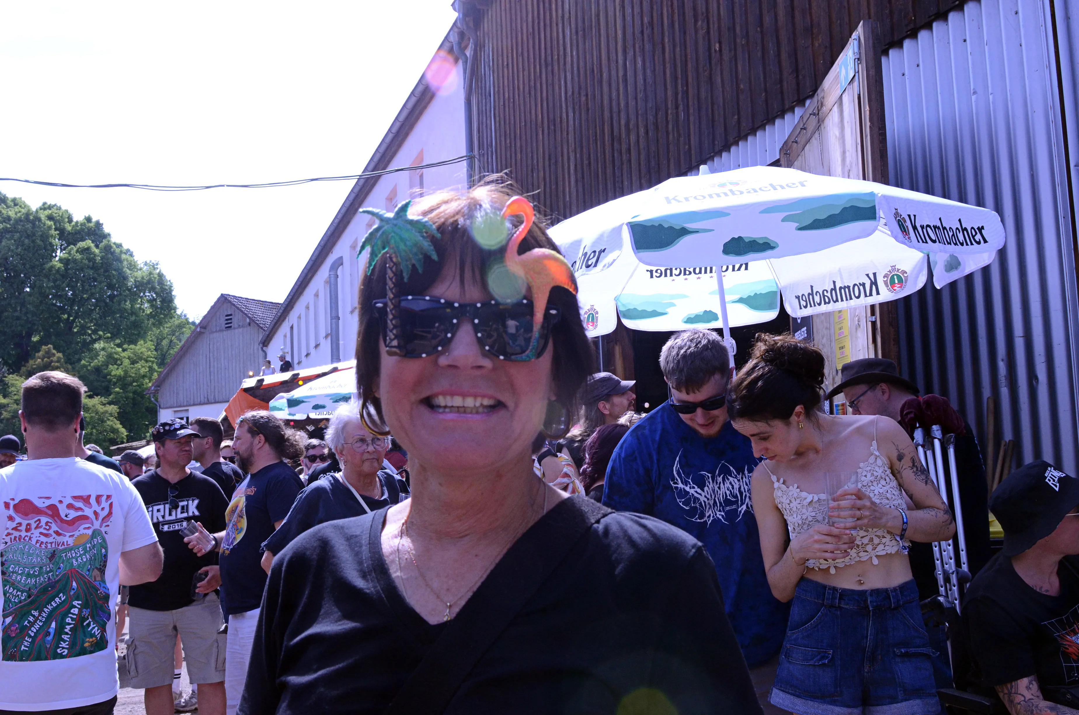 Nahaufnahme einer Frau mit auffälligem Kopfschmuck und Sonnenbrille inmitten einer Menschenmenge auf dem Immecke Rock Festival.