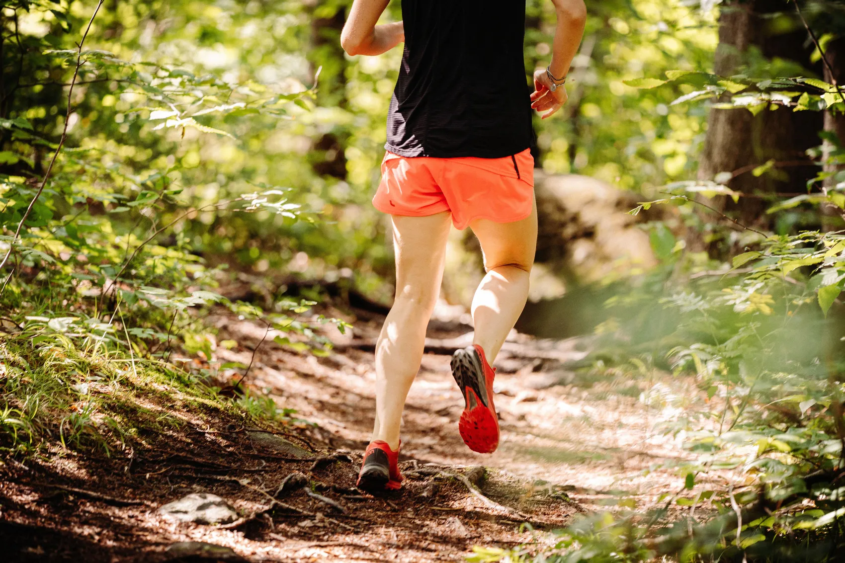Läuferin mit roter Sportkleidung auf einem Waldweg, während eines Crosslaufes im Gelände.