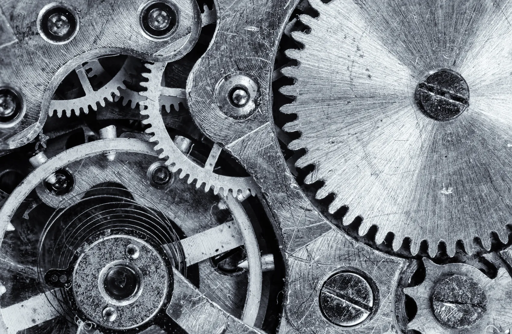 Nahaufnahme von Zahnrädern und mechanischen Teilen aus Metall, die ein komplexes Uhrwerk oder eine Maschine bilden.