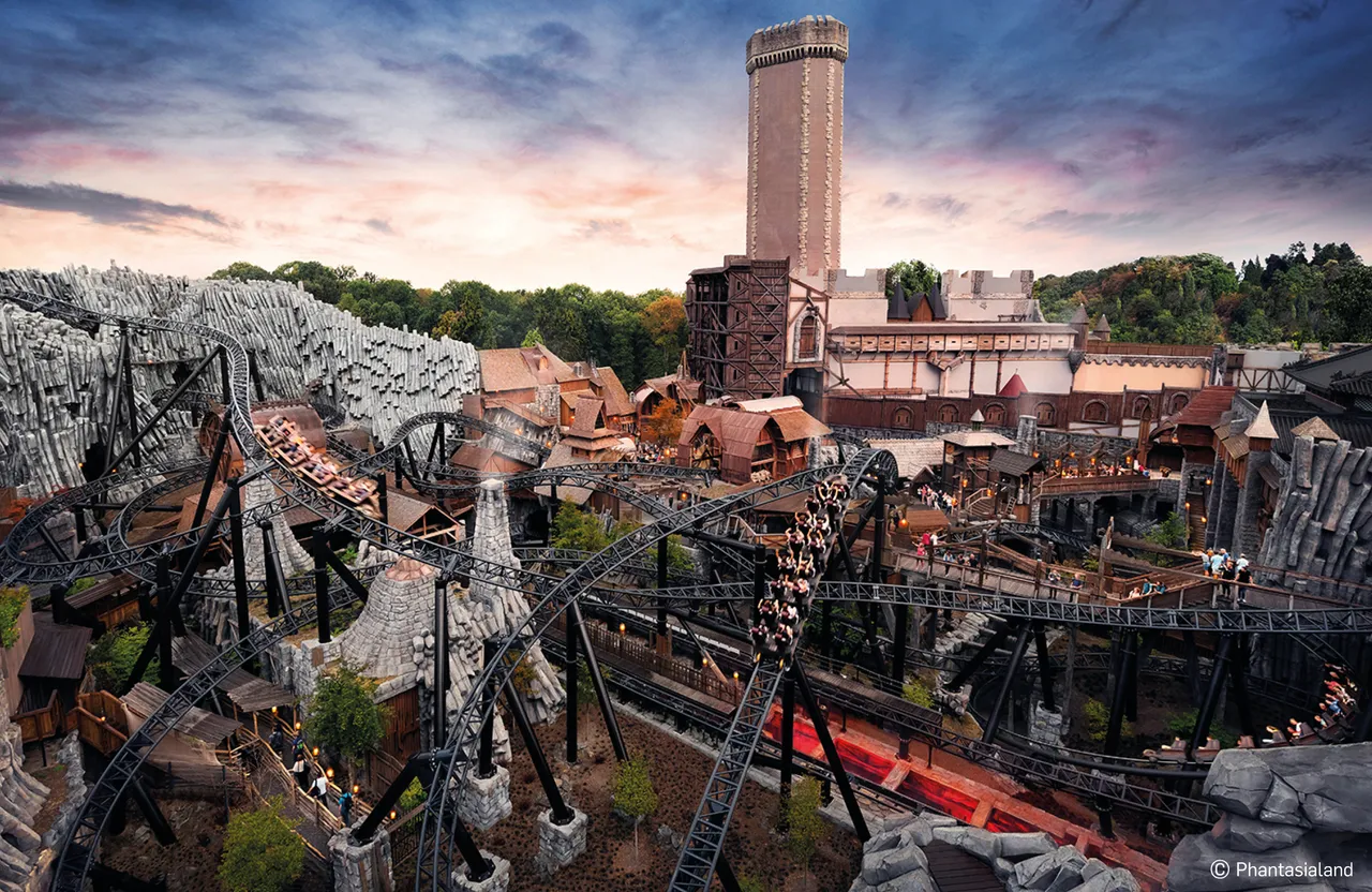 Eine dunkle Achterbahn schlängelt sich durch eine mittelalterlich anmutende Kulisse mit Türmen und Fachwerkhäusern im Phantasialand Freizeitpark in Brühl.