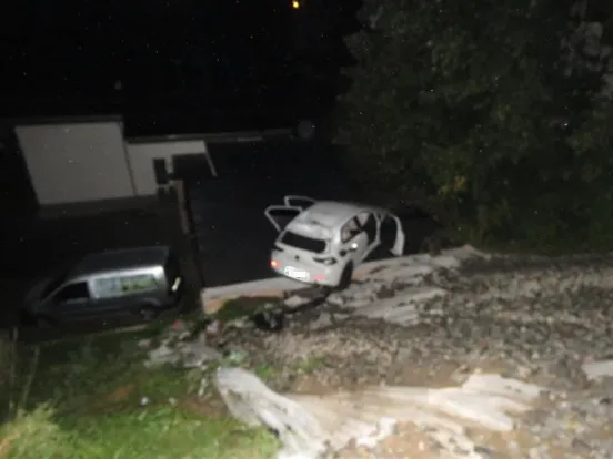 Ein weißes Auto steht auf dem Dach einer Garage bei Nacht.